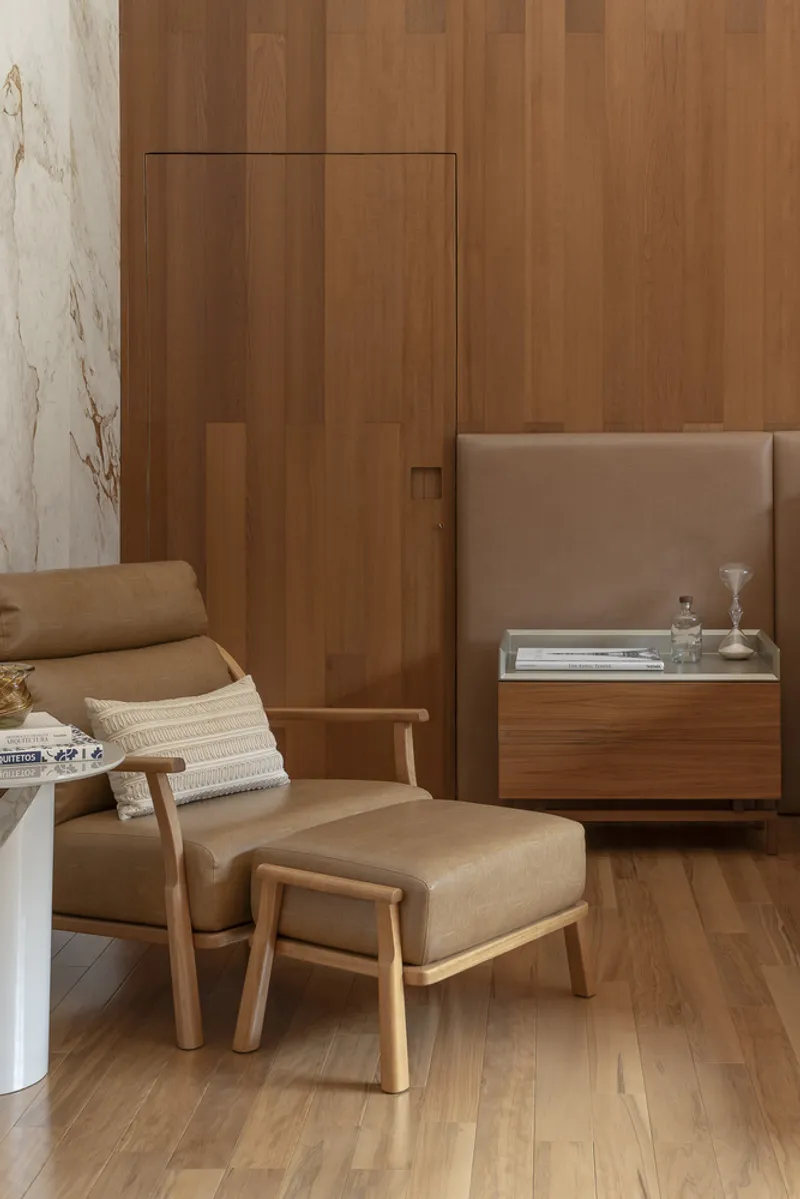 Bedroom corner with recessed timber wall panel, upholstered lounge chair and floating walnut nightstand
