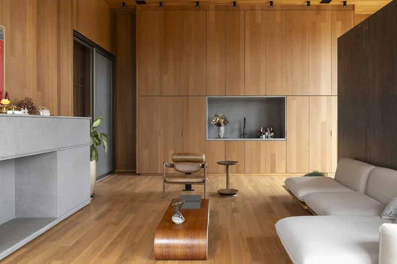 Living area with timber-paneled walls featuring a recessed display niche and timber flooring