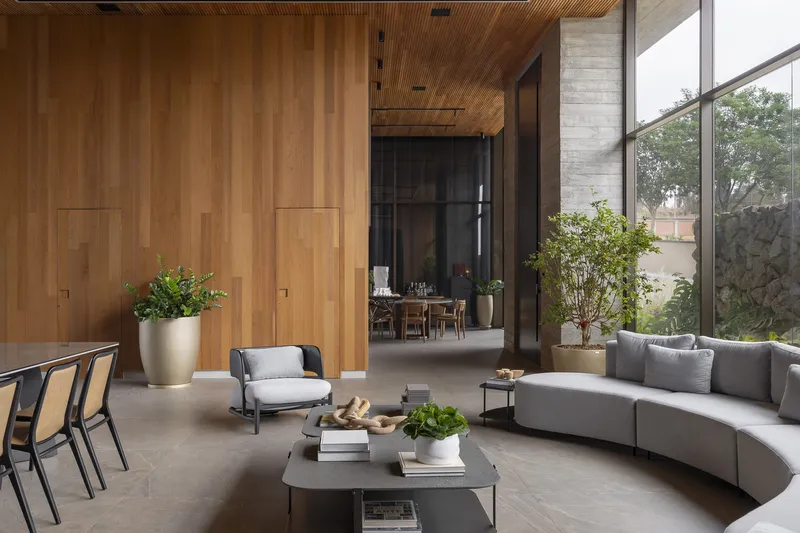 Double-height living room with vertical timber paneling and floor-to-ceiling windows overlooking garden plantings