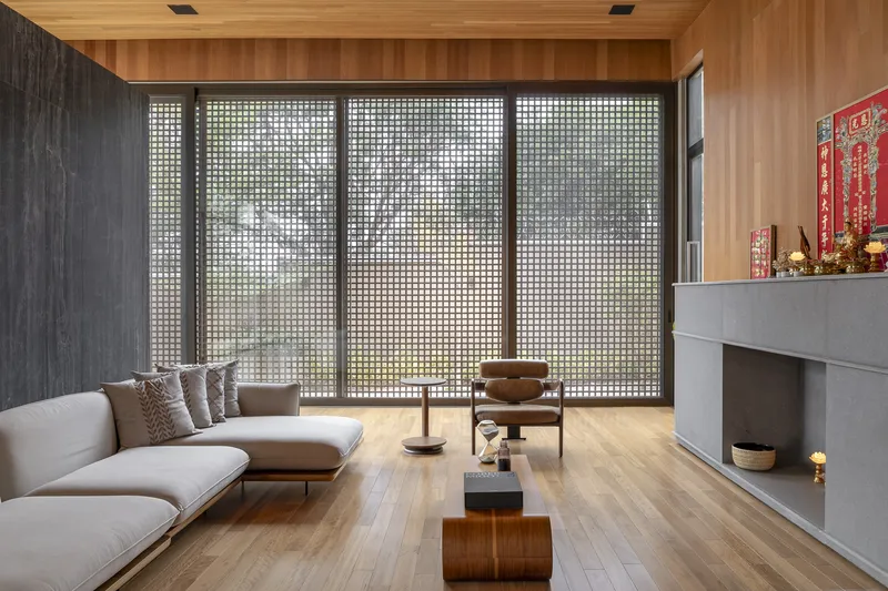 Living space with perforated metal screens diffusing natural light beneath a timber-lined ceiling