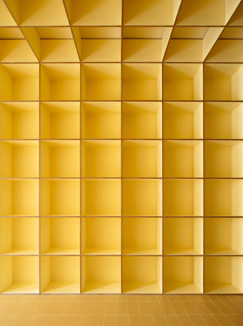 Yellow grid of recessed square niches in a coffered ceiling above tiled flooring