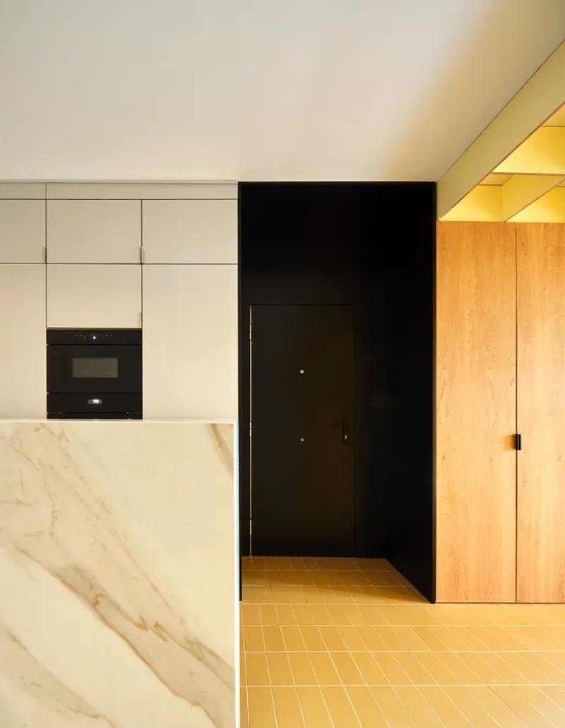 Black doorway framed by white cabinetry, yellow tile floor, and illuminated timber joinery