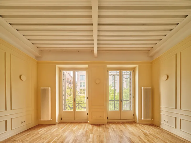 Room with exposed timber batten ceiling, paneled walls, and paired French doors opening to balconies