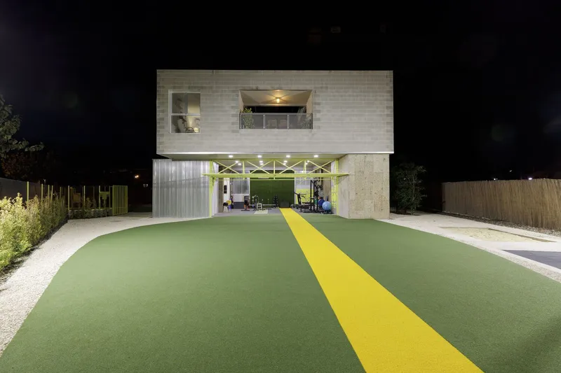 Night view of the two-story facade with yellow diagonal stripe leading to the sheltered entrance