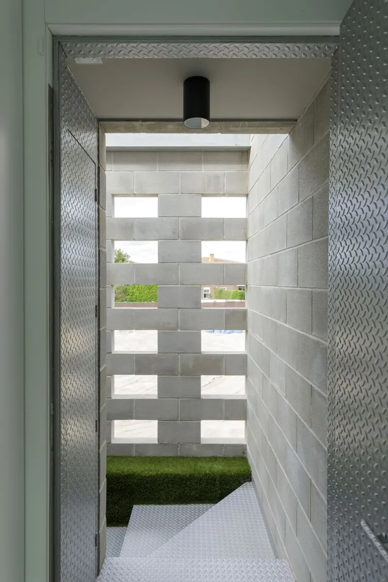 Entry corridor with concrete block walls featuring horizontal window slots framing green lawn beyond