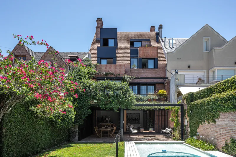 Rear garden view showing tiled roof extension above green-roofed pavilion and pool in summer