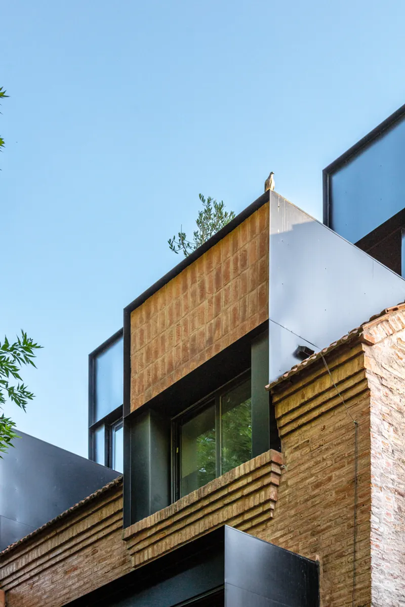 Facade composition with terracotta tile panel and horizontal timber louvre screen flanked by white rendered walls