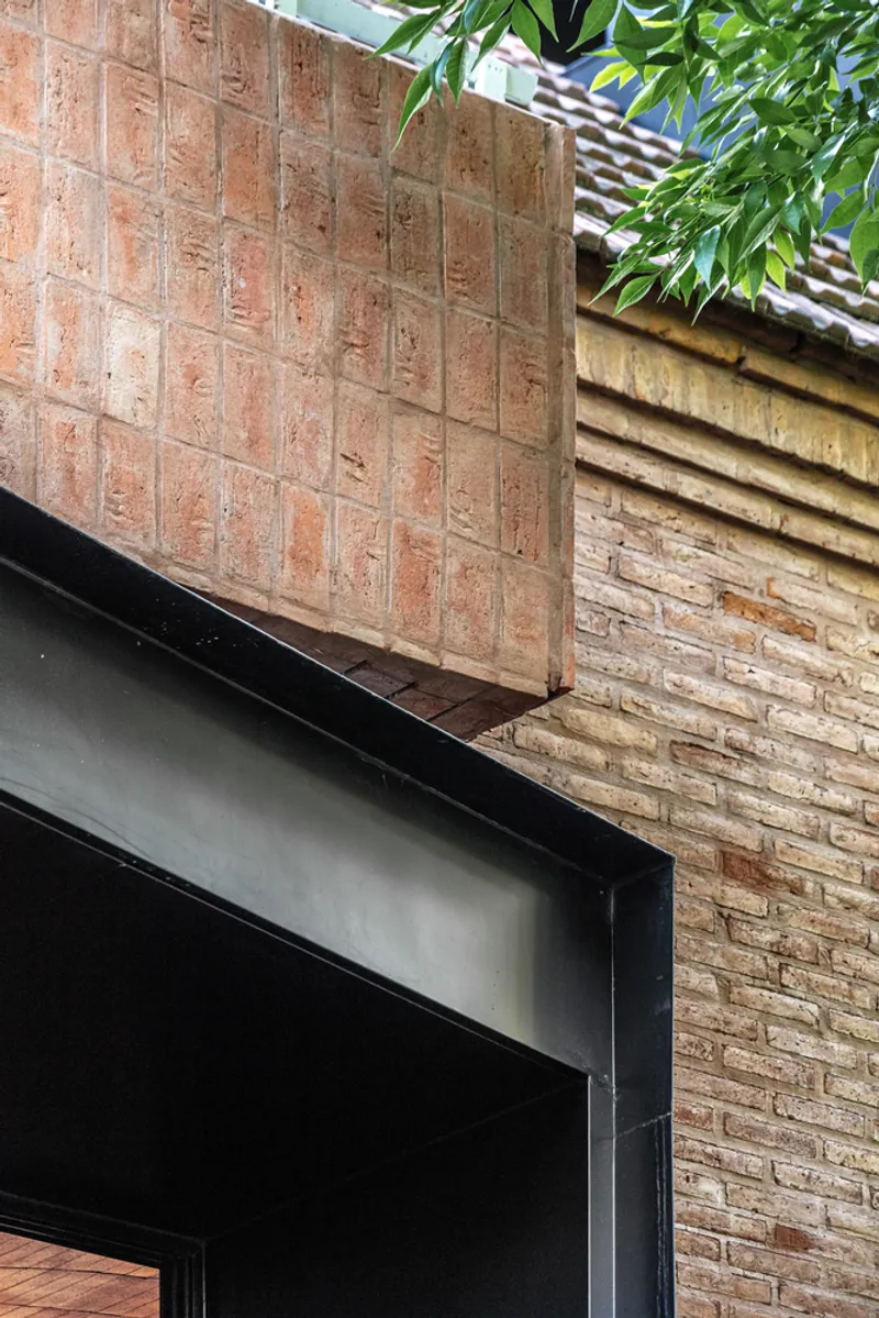 Detail of the textured brick planter meeting black steel framing and adjacent brick wall
