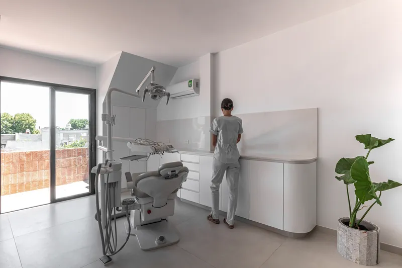 Dental office with white cabinetry and person standing near equipment under skylight