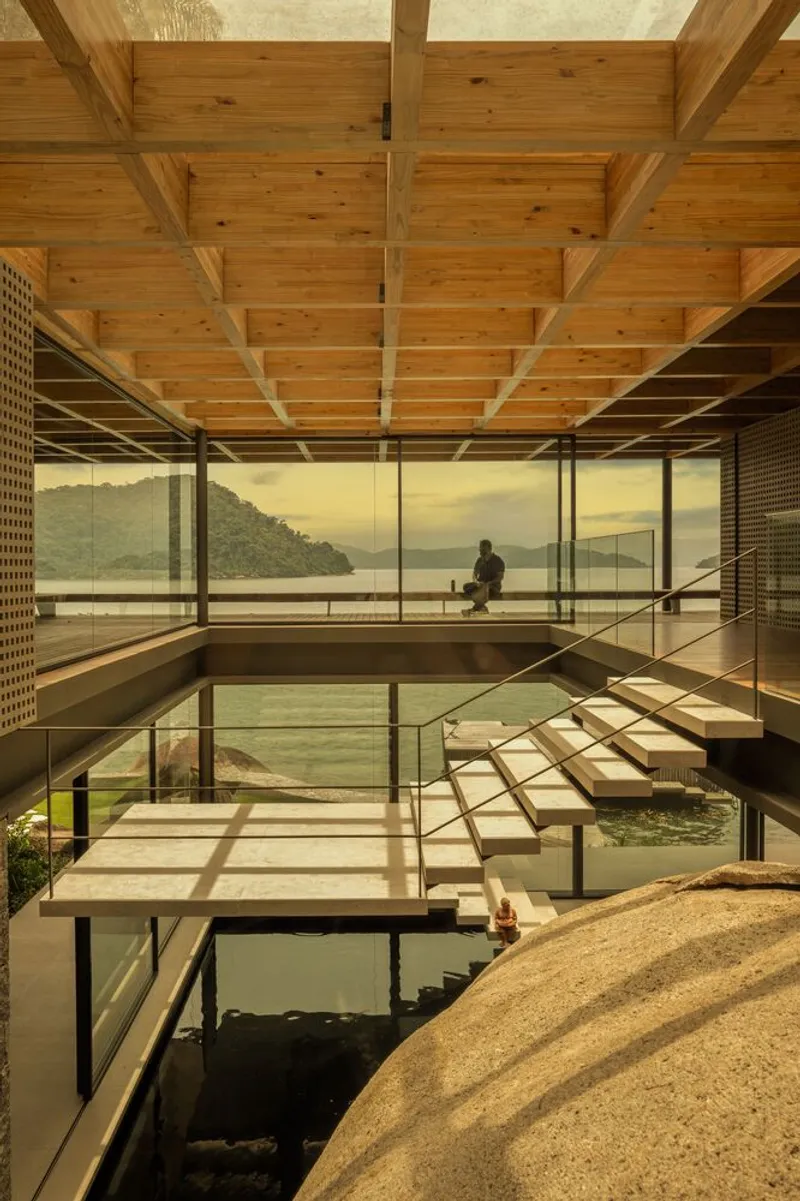 Multi-level interior courtyard with water features and timber-framed ceiling overlooking the lake through floor-to-ceiling glass
