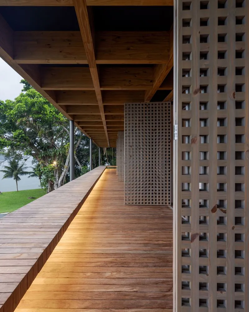 Covered timber deck with perforated brick screen wall and coffered wood ceiling overlooking garden