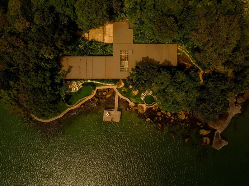 Drone view of flat roof volumes with illuminated pathways threading through garden at dusk