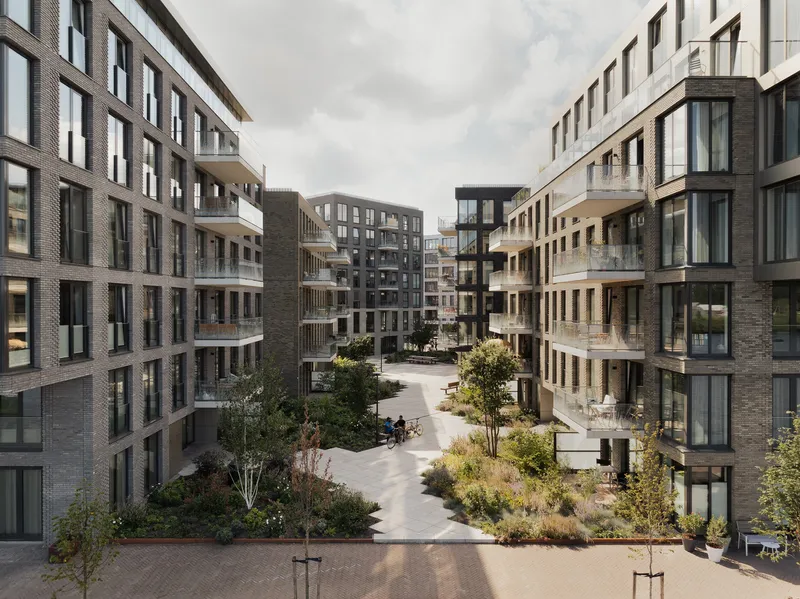 Shared courtyard with planted beds and paved pathways framed by brick residential blocks
