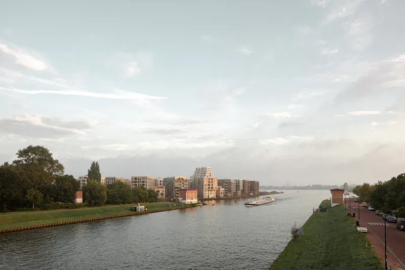 Long canal view with residential blocks lining the waterfront under an evening sky