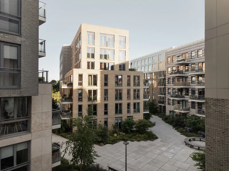 Cream-colored block with recessed balconies overlooking a landscaped courtyard at dusk