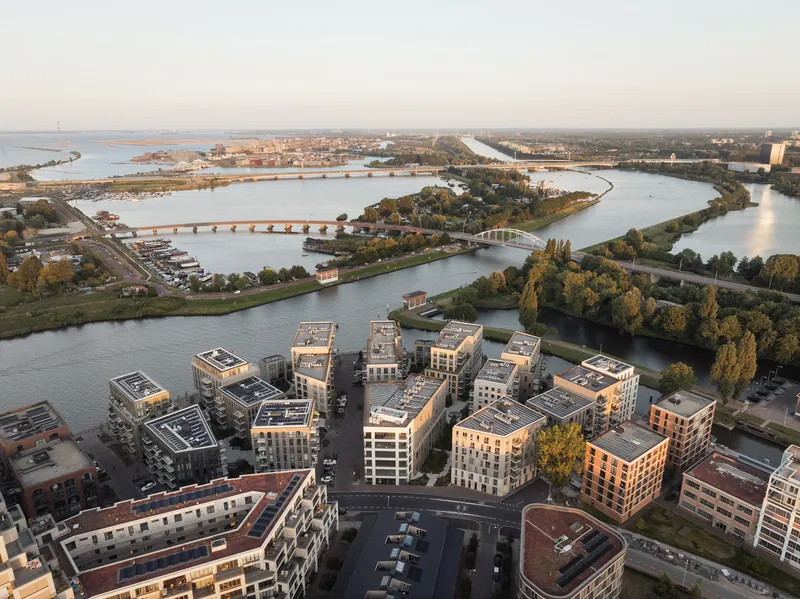 Aerial view of the housing development with rooftop solar panels beside a winding river at dusk