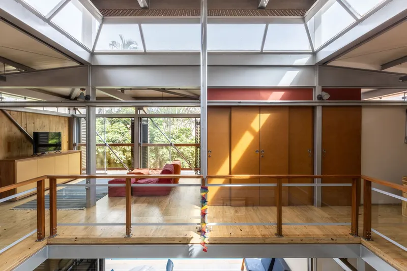 Upper level living space with timber guardrail overlooking the lower floor under a skylight