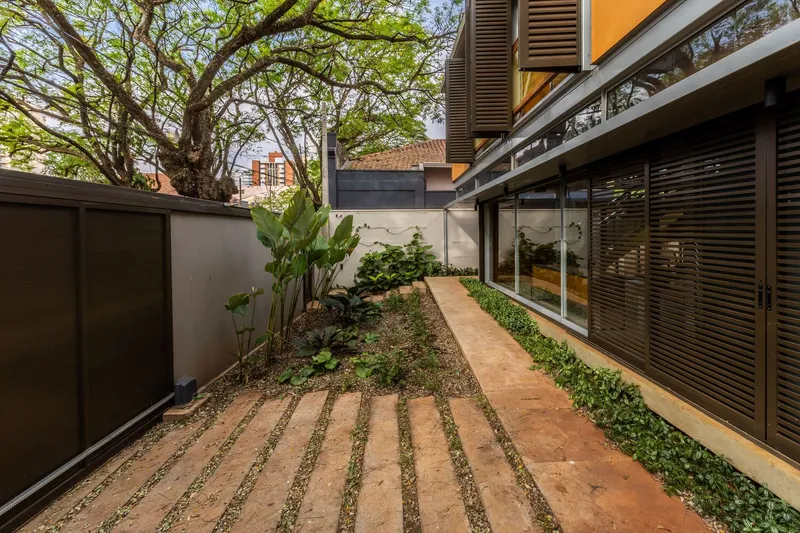 Side garden with terracotta paver path laid in gravel between planted beds and boundary wall