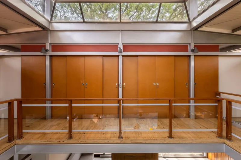 Upper level mezzanine with timber guardrail and wood-paneled storage wall beneath a clerestory skylight