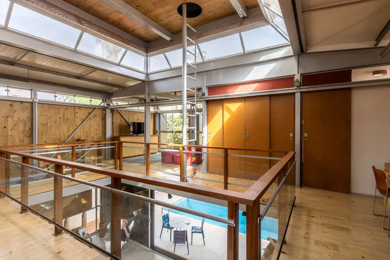 Double-height interior with timber ceiling, clerestory windows, and mezzanine walkway overlooking lower level