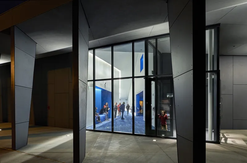Lobby entrance with floor-to-ceiling glass doors framing a view of pedestrians in the courtyard at dusk