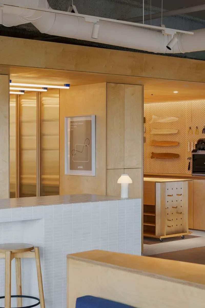 Reception counter with white tile facing and pegboard wall beside plywood-clad elevator doors