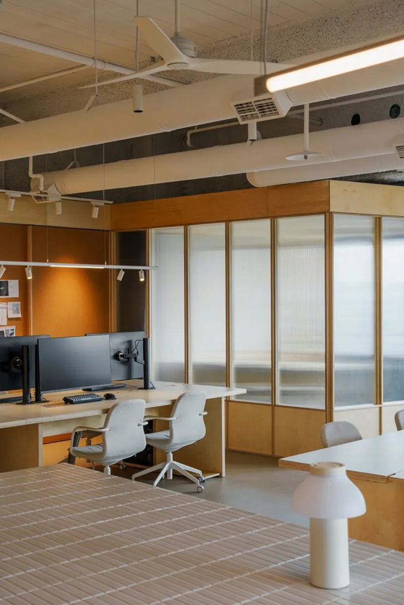 Workstation area with translucent sliding partitions in timber frames and white task chairs