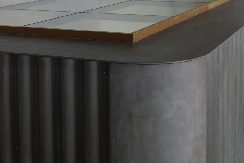 Detail of curved corrugated metal surface with brass trim along the top edge
