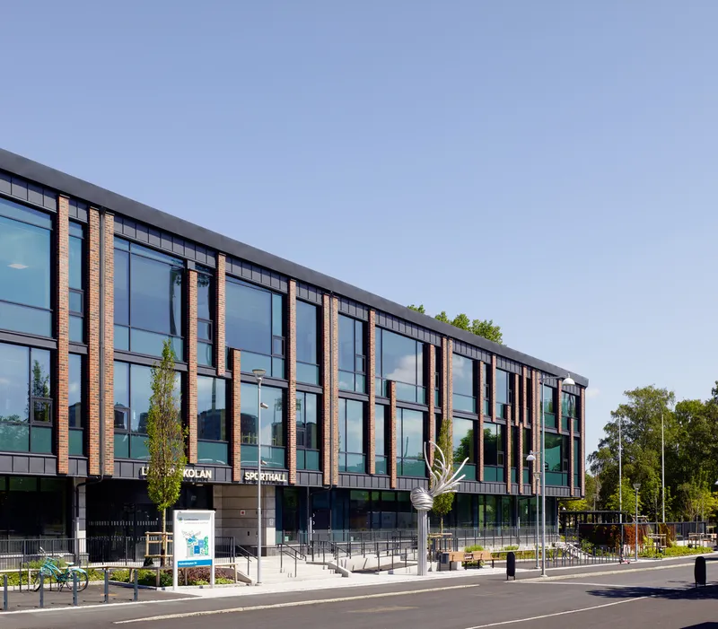 Street view of the glass and timber-paneled facade with bicycle racks and signage at ground level