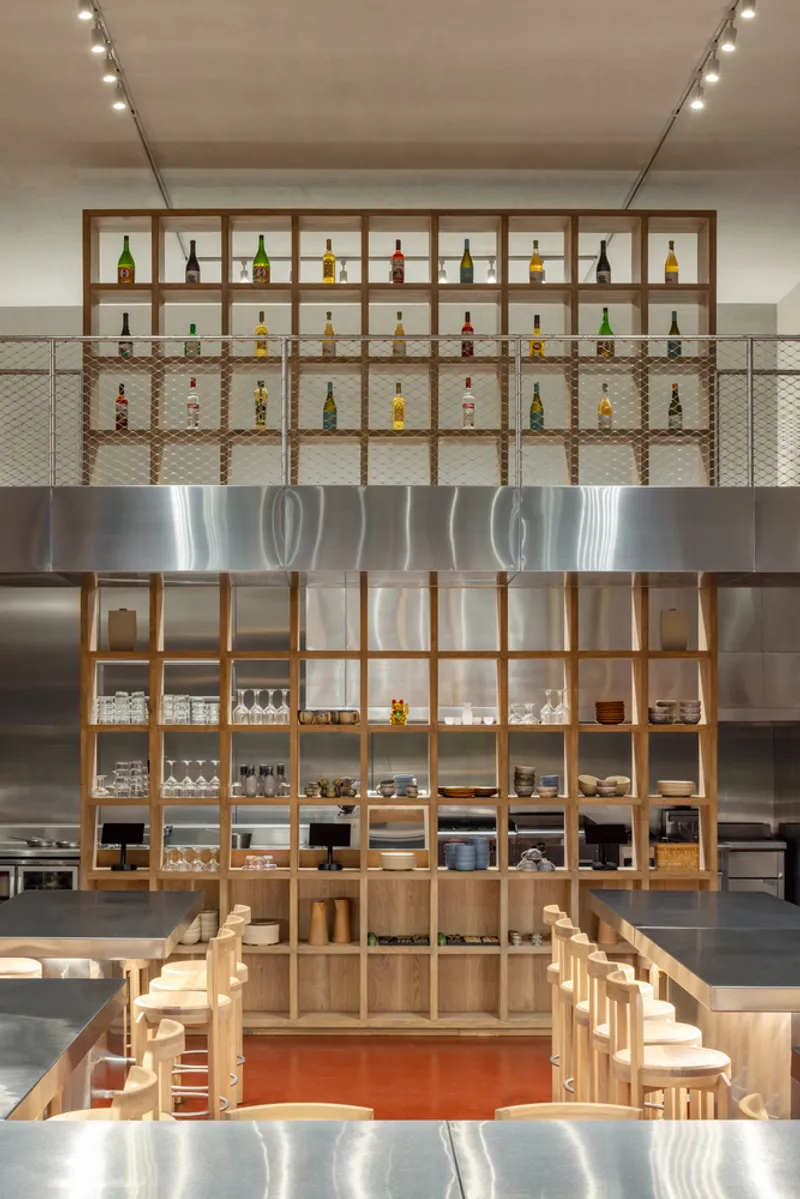 Double-height timber shelving unit displaying bottles and dishware above the central island