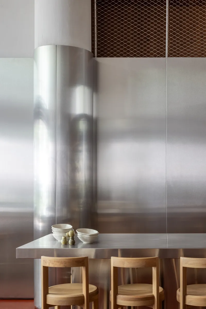 Close-up of cylindrical stainless steel column meeting metal counter with mesh grilles overhead