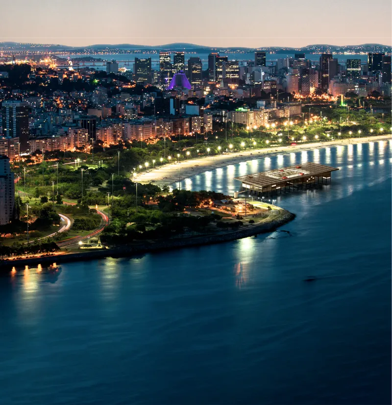 Evening aerial view of the floating platform with solar arrays beside an illuminated coastal parkway
