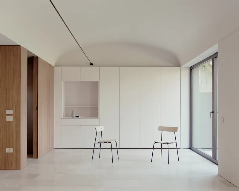 Interior room with white built-in cabinetry, two chairs and vaulted ceiling under soft daylight