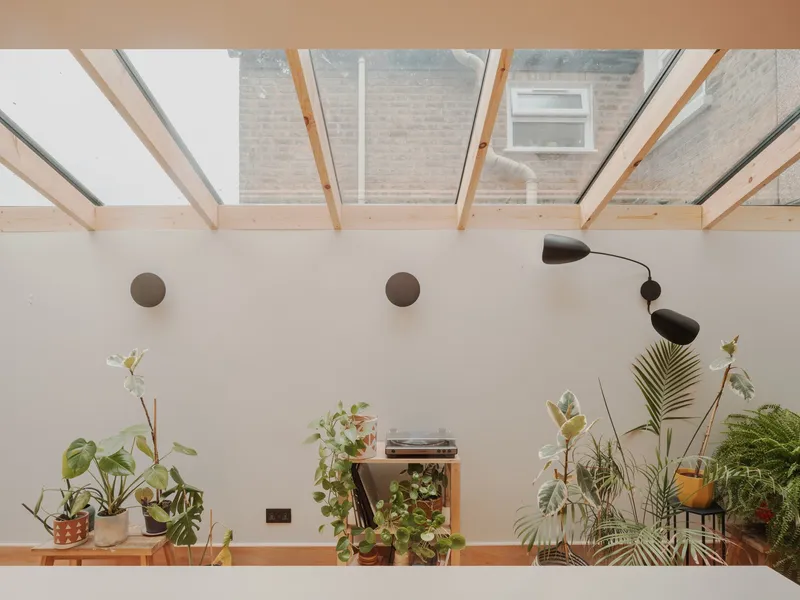 View through the glazed roof structure to the neighboring brick facade and planted shelf below