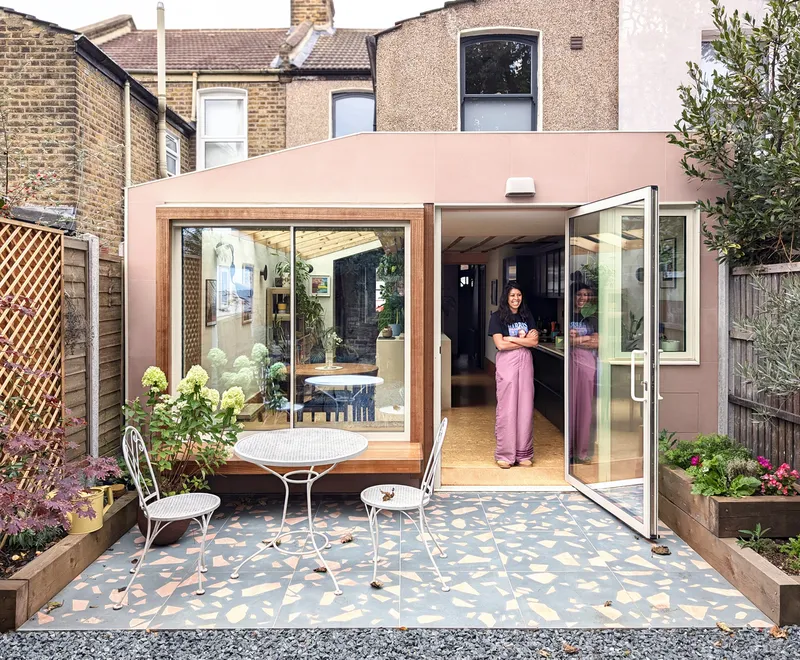 Rear garden courtyard with pink extension featuring timber-framed glazing and patterned terrazzo floor tiles