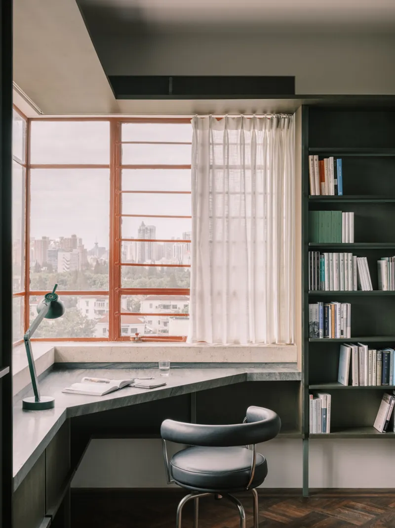 Built-in corner desk with timber-framed window overlooking the cityscape and translucent linen curtain