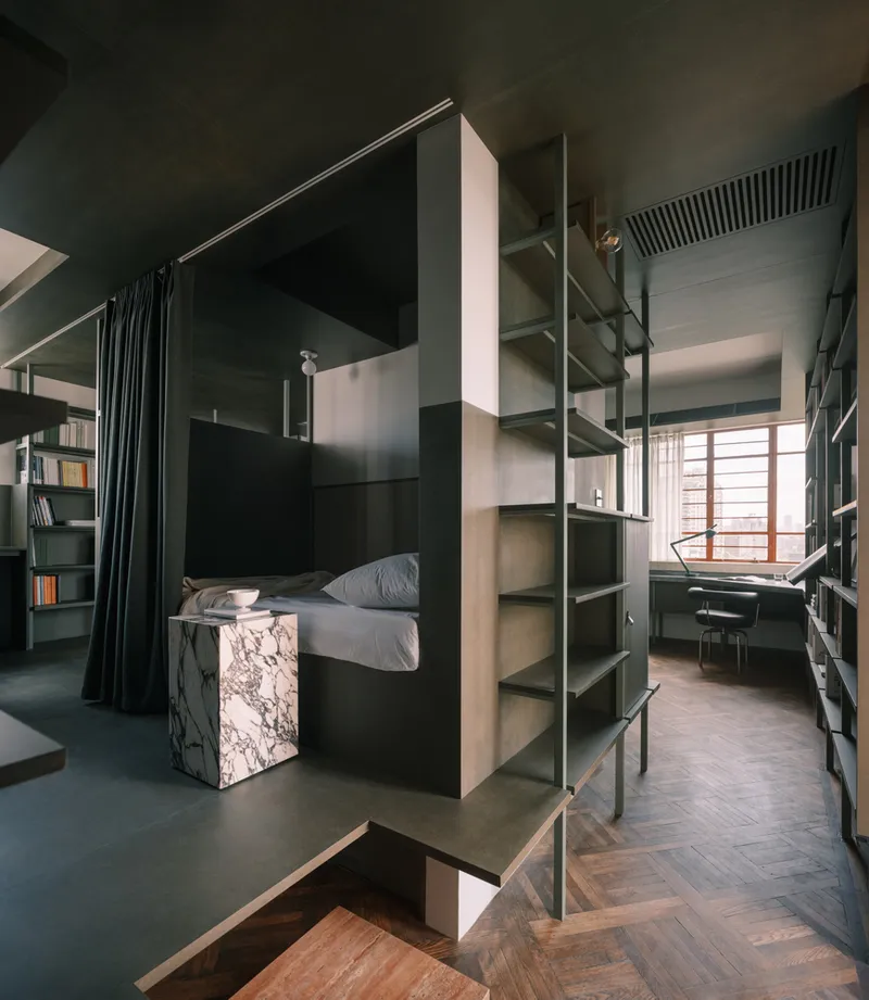 Elevated sleeping platform with integrated ladder and steel shelving beside a workspace with timber shutters