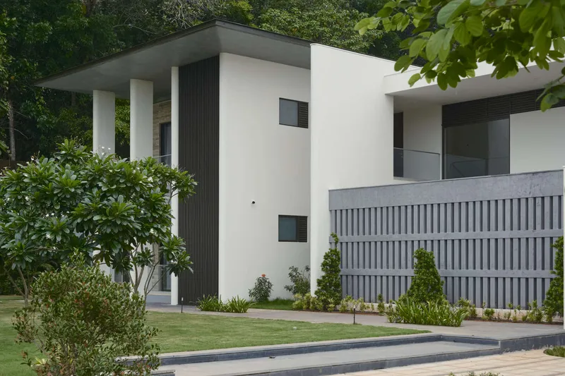Side elevation showing white stucco volumes with dark vertical cladding and landscaped planting beds