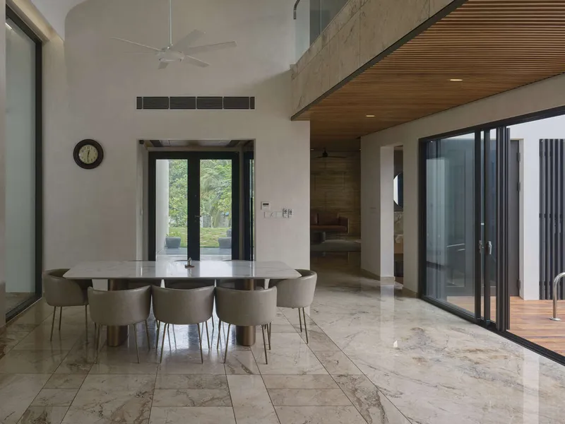 Open dining area with polished stone flooring and timber slatted ceiling overlooking the garden