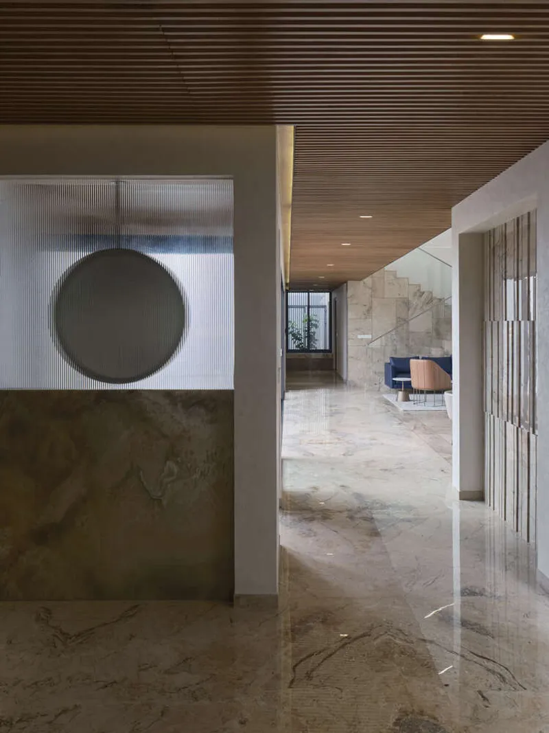 Interior corridor with ribbed timber ceiling and circular portal opening through a translucent glass screen