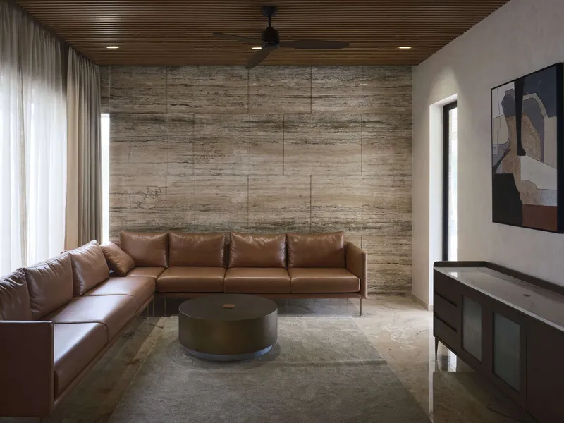 Living room with horizontal stone cladding wall and timber ceiling above a leather sectional sofa