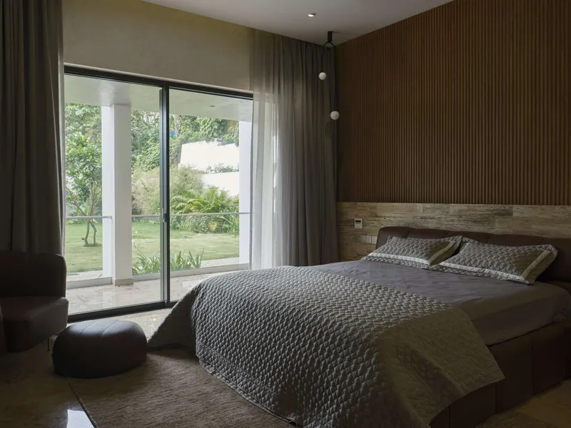 Bedroom with timber slat wall and reclaimed wood headboard overlooking a garden through sliding glass doors
