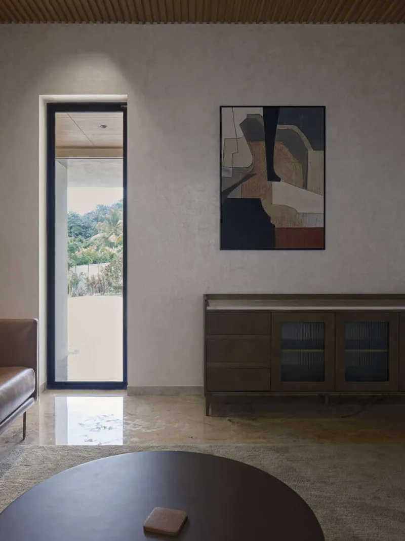 Living room with polished concrete floor and narrow doorway framing a view of distant hills in daylight