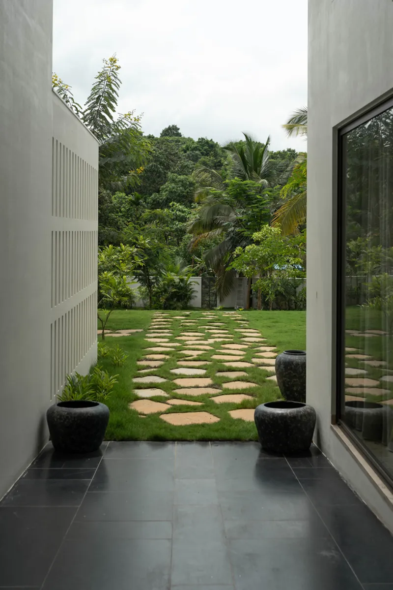 View from interior through concrete columns toward stepping stone path with black planters flanking threshold