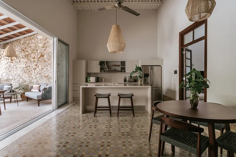 Kitchen island with bar stools under exposed timber ceiling beams and a woven pendant light