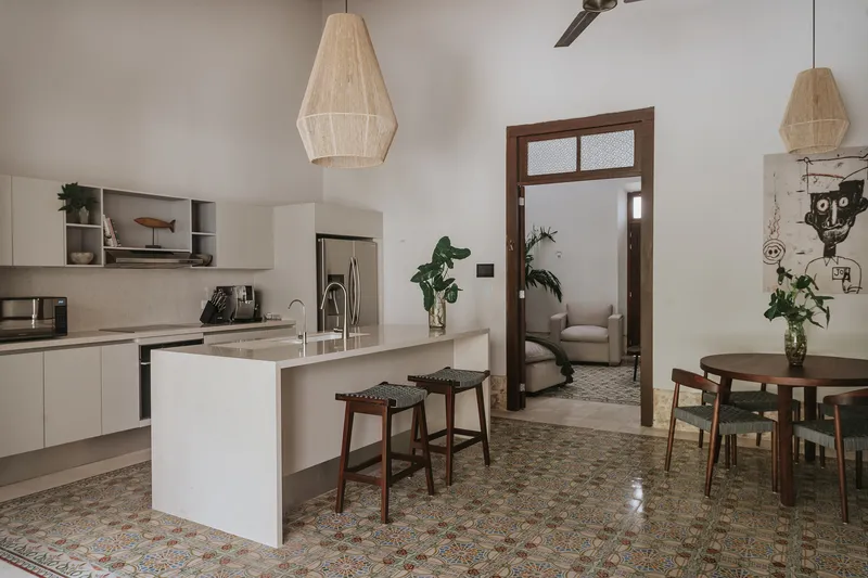 Open-plan kitchen and dining area with patterned cement tile flooring and woven pendant lights overhead