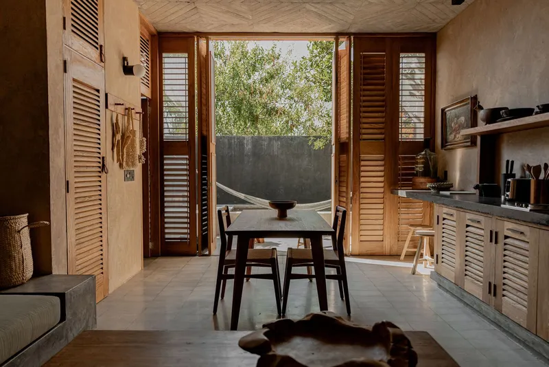 Interior view through open louvered timber doors to a hammock suspended in the courtyard beyond