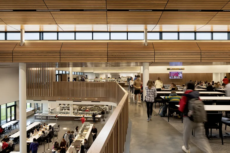 Interior bridge connecting upper levels across the dining hall with people in motion