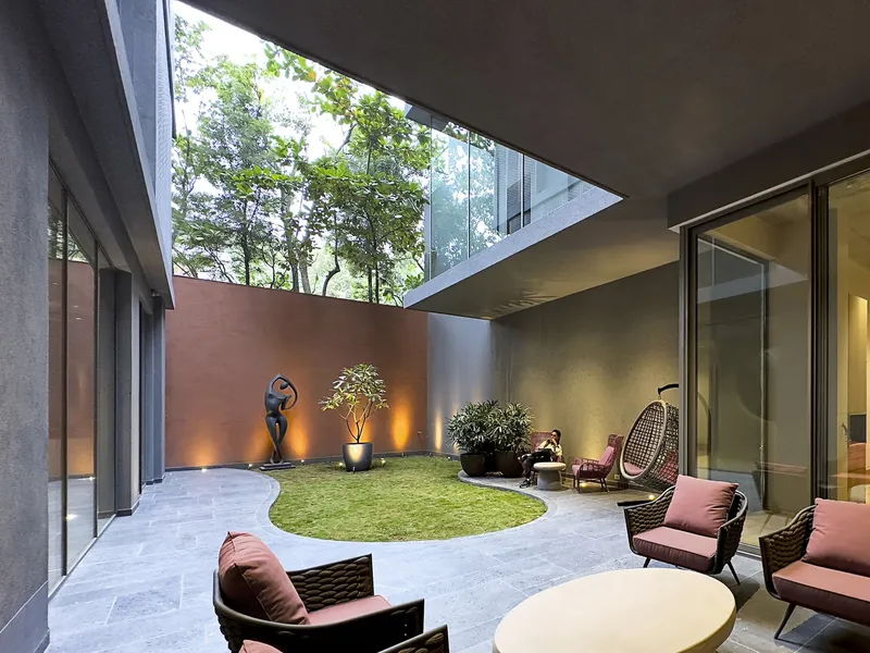 Interior courtyard with circular lawn and trees visible through skylight opening above