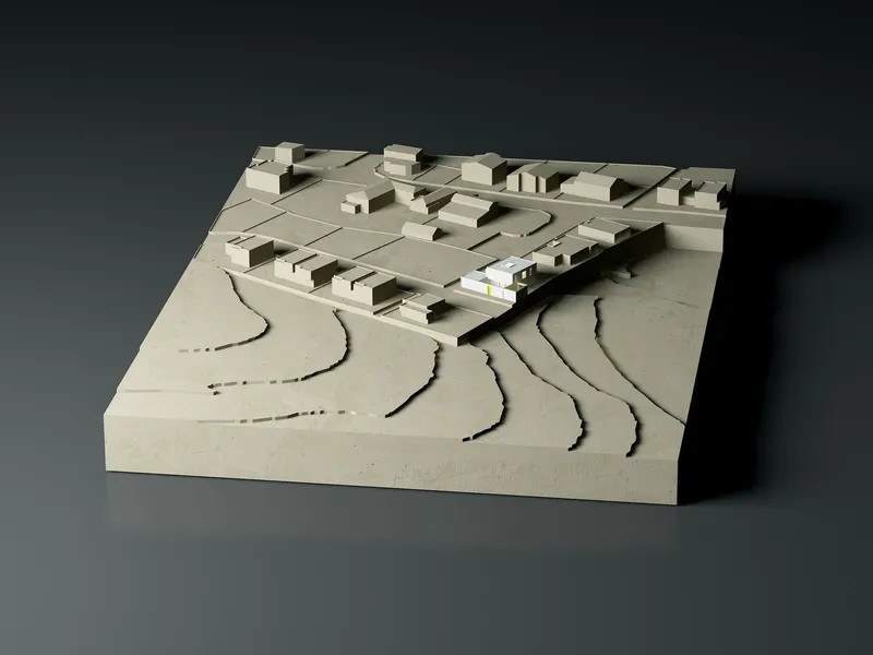 Physical model showing site topography with carved contours and clustered buildings on sloped terrain